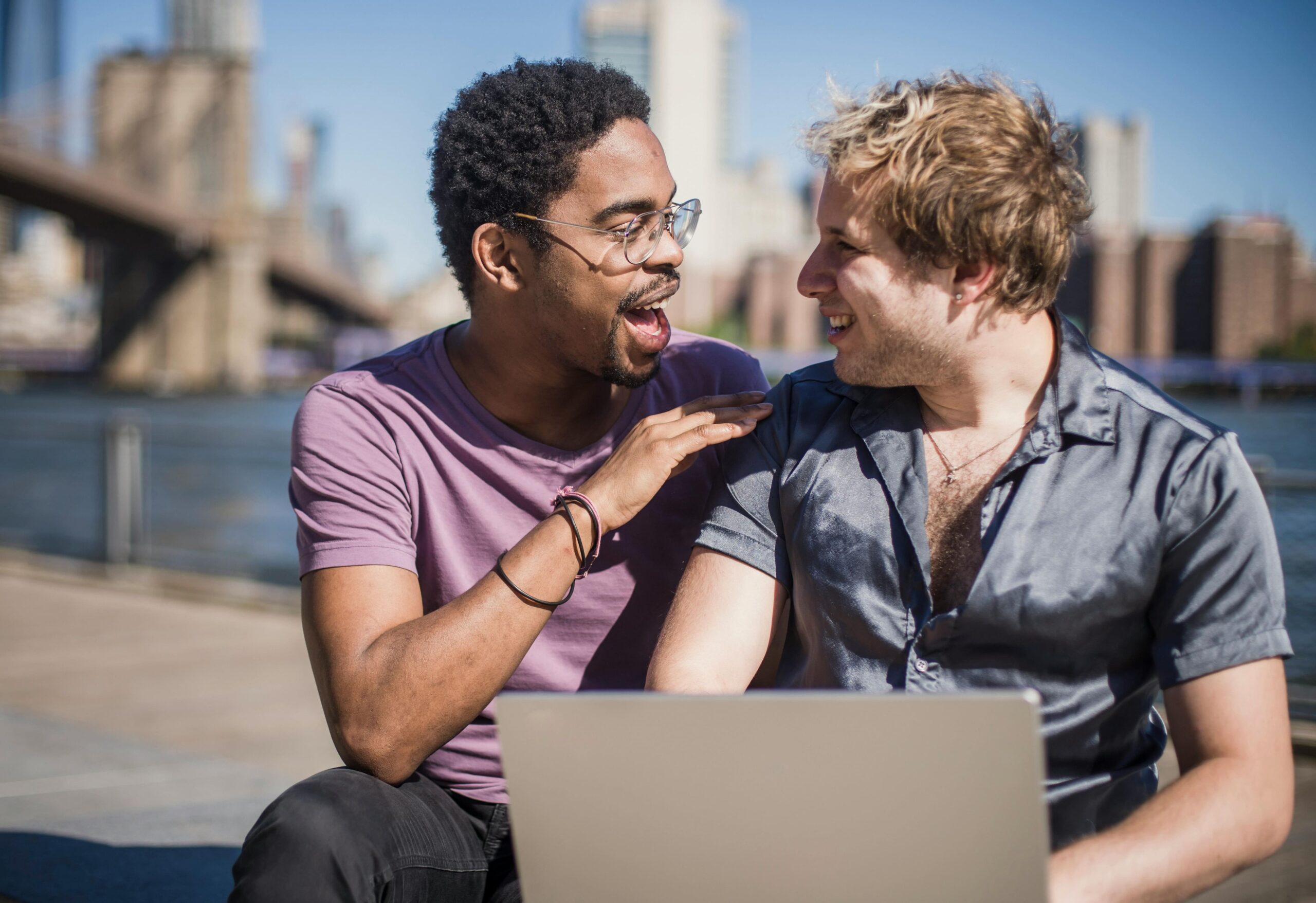 Couple sitting on the pavement with laptop